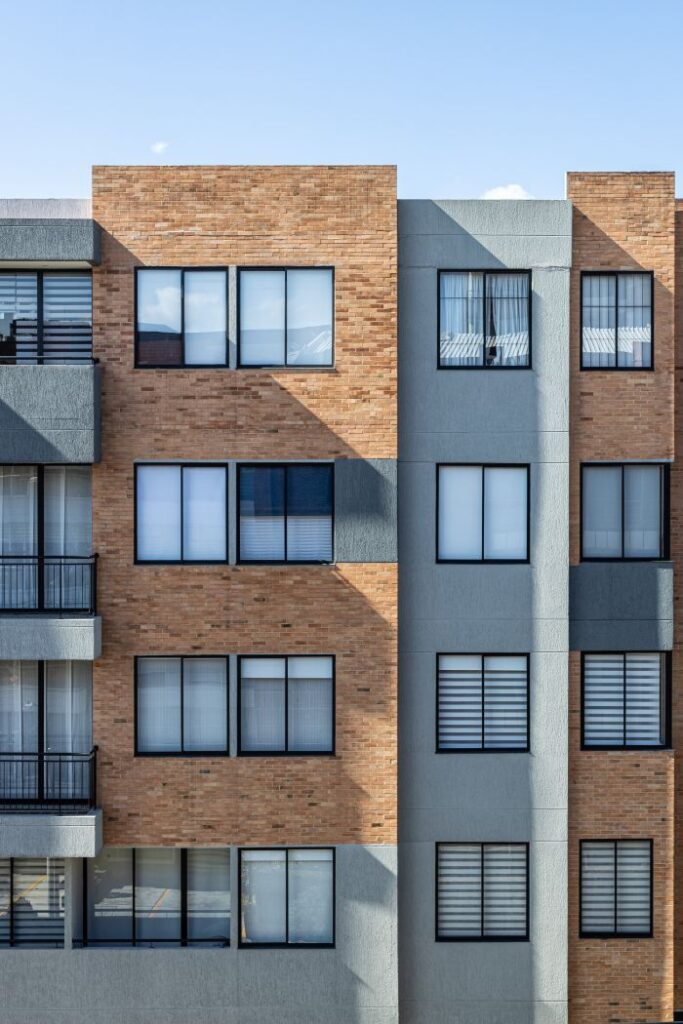 A modern apartment building showcasing a mix of brick and concrete elements under clear skies.